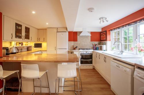 a kitchen with orange walls and white cabinets at Jasmine Cottage in Kelsale
