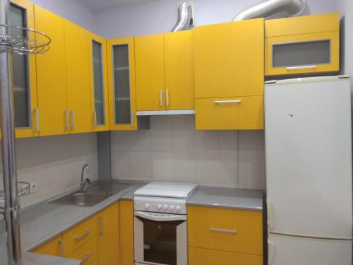 cocina con armarios amarillos y nevera blanca en Apartment on Sobornaya street, en Rivne