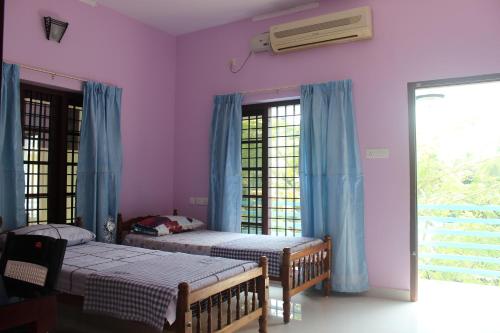 two beds in a bedroom with purple walls at Puthenchirayil Homestay in Trivandrum