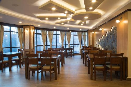 uma sala de jantar com mesas, cadeiras e janelas em Jai Hotels em Darjeeling