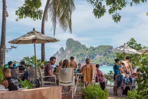 a group of people sitting at tables on the beach at PP Charlie Beach Resort- SHA Plus in Phi Phi Don