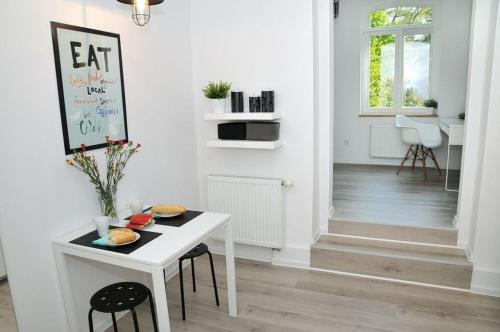 a white kitchen with a white table and chairs at Apartament 100m od morza in Sopot