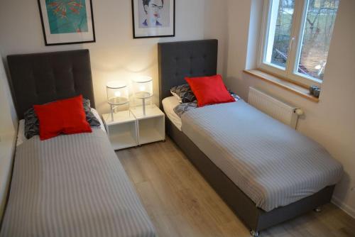 two beds with red pillows in a bedroom at Apartament 100m od morza in Sopot