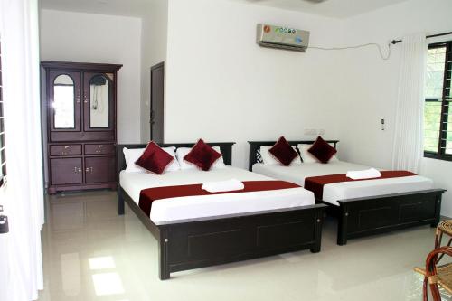 a bedroom with two beds with red pillows at Munroe Island Lake Resort in Munroe Island
