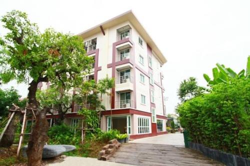 a pink and white building with a tree in front of it at The Loft Resort Bangkok in Bangkok
