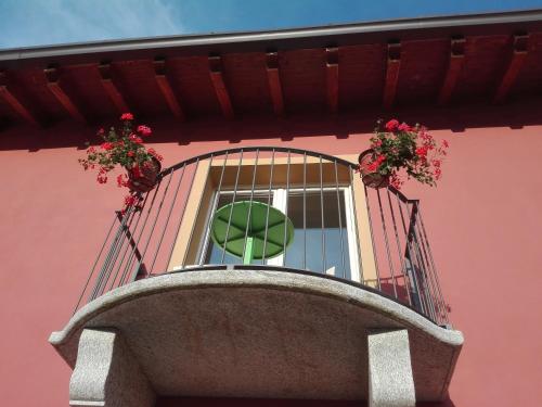 a window on a pink building with flowers on it at Hotel Bocciolo in Orta San Giulio