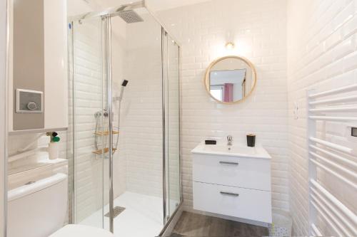Un baño blanco con ducha y lavabo. en PARENTHESE - Le Marqui, en Lourdes