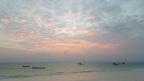 a group of boats in the ocean under a cloudy sky at White Sands in Paje