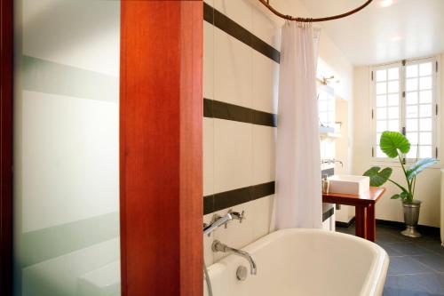 La salle de bains est pourvue d'une baignoire blanche et d'un mur rayé. dans l'établissement La Porte Rouge - The Red Door Inn, à Saintes