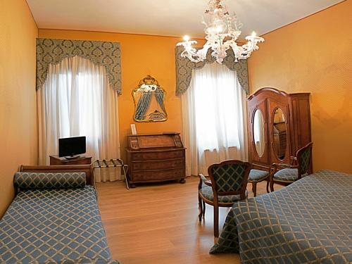 1 dormitorio con cama, escritorio y lámpara de araña en Hotel Locanda Canal, en Venecia