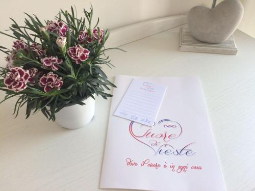 a table with a wedding invitation and a vase of flowers at Cuore di Vieste in Vieste