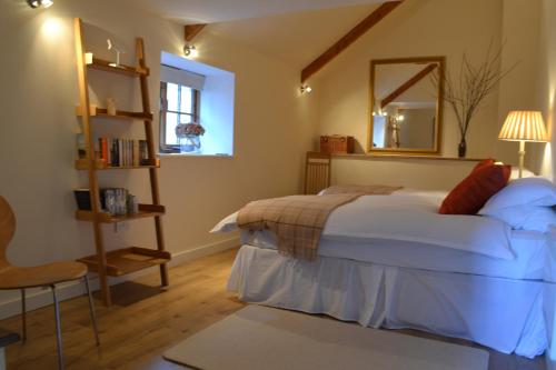 a bedroom with a bed and a mirror and a chair at Tremodrett House Barn in Bodmin