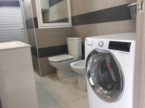 a bathroom with a washing machine and a toilet at First line Apartment in Alicante