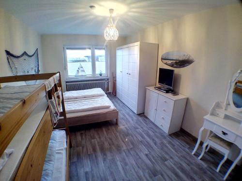 a room with a bed and a desk with a television at Ferienwohnung Deichstr De Lorenzo in Carolinensiel