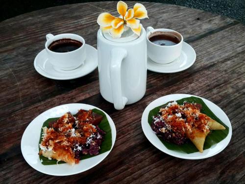 a table with plates of food and two cups of coffee at Lila Stana - Sidemen Homestay in Sidemen