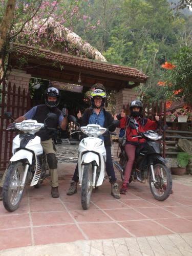 three people on motorcycles parked in front of a building at Green Hill Hostel & Tour in Ha Giang