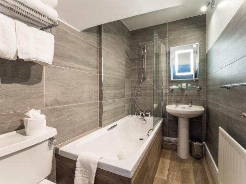 a bathroom with a tub, sink, toilet and bathtub at Lyzzick Hall Hotel in Keswick