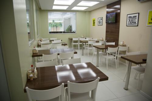a dining room with tables and white chairs at Hotel Padre Cícero in Juazeiro do Norte