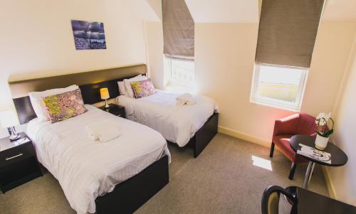 a hotel room with two beds and a chair at Mannin Hotel in Douglas
