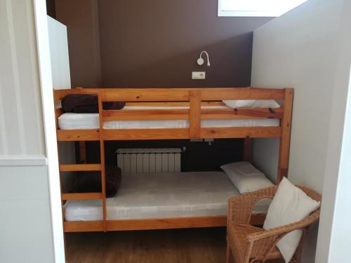 2 Etagenbetten in einem kleinen Zimmer mit einem Stuhl in der Unterkunft Albergue Ultreia in Arzúa