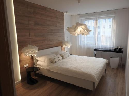 a bedroom with a bed with a wooden headboard and lights at Apartament z ogrodem Wiśniowy Sad in Kołobrzeg