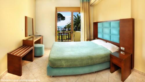 a bedroom with a large bed and a balcony at Vergos Hotel in Vourvourou