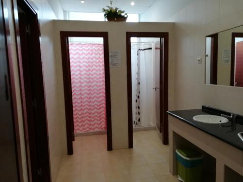 
a bathroom with a shower, sink, and mirror at Albergue O Bordón in Cee
