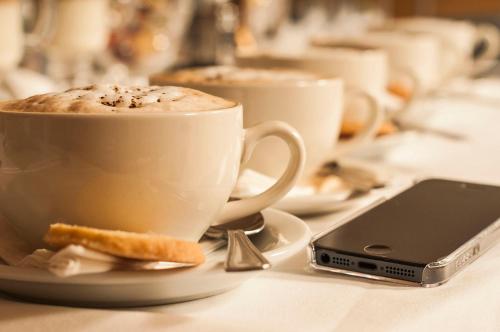 a cup of coffee on a table next to a cell phone at The Manor Hotel in Crickhowell