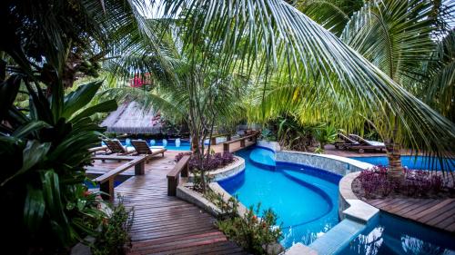 an image of a resort swimming pool with palm trees at Sombra e Água Fresca Floresta in Pipa