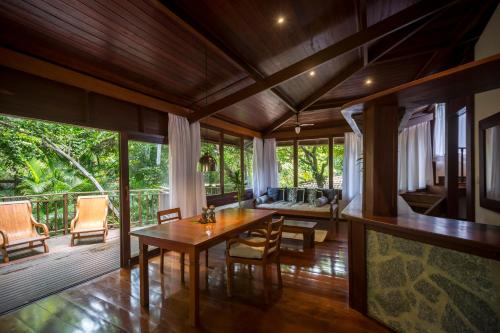 a living room with a wooden table and chairs at Sombra e Água Fresca Floresta in Pipa