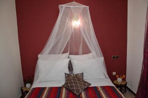 a bedroom with a bed with a canopy and pillows at Ferme D"Hote Lala Fatima in Aïn Leuh