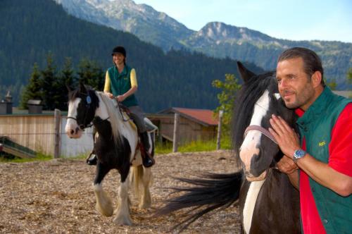 a man standing next to a woman riding a horse at Wohlfühlresort und Feriengut Martinerhof in Sankt Martin am Tennengebirge