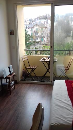 ヴィレ・シュル・メールにあるRésidence de la Plageのベッド1台、バルコニー(テーブル、椅子付)が備わる客室です。