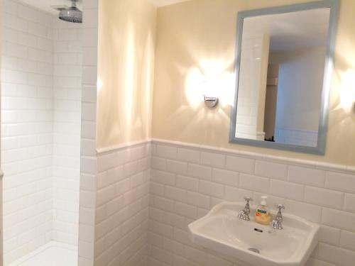 a white bathroom with a sink and a mirror at Bank Ground Farm in Coniston