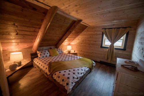 a bedroom with a bed in a log cabin at Les 3 Cavaliers - Les Chalets Spa Canada in La Malbaie