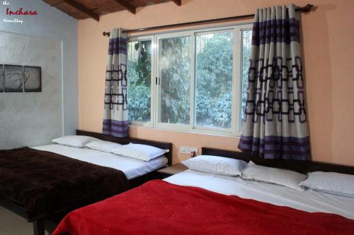 two beds in a room with a window at The Inchara Hill View HomeStay in Chikmagalūr