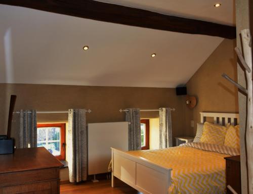 a bedroom with a bed and a desk and windows at Les houx de Mathieu in Engis