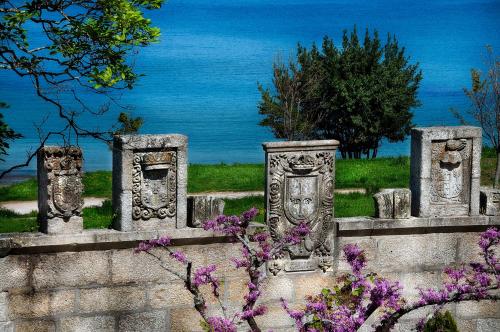 a stone fence with statues and purple flowers at Pazo Los Escudos Hotel Spa & Resort in Vigo
