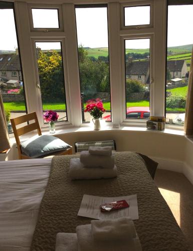 a bedroom with a bed with towels on it with windows at Meadow Lodge in Tideswell