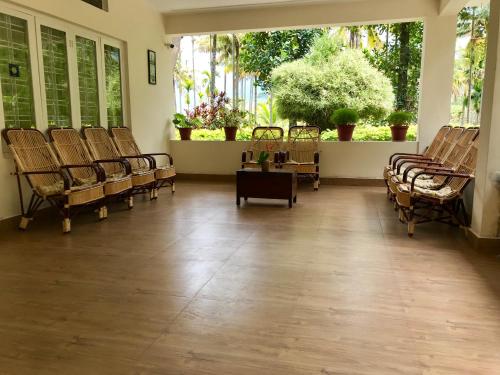a large room with chairs and plants and windows at Davis Farm House in Marayoor