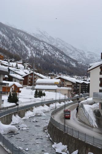 a train traveling down a road in a town with snow at Haus Orta in Zermatt