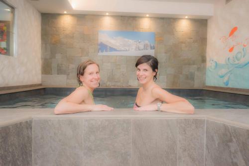 two women are sitting in a hot tub at Hotel Le Alpi in Livigno