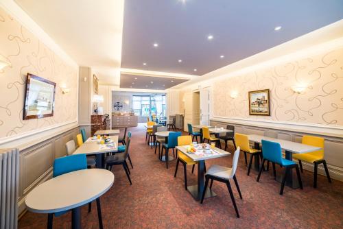 un restaurant avec des tables et des chaises dans une salle dans l'établissement The Originals Boutique, Hôtel Normandie, Auxerre, à Auxerre