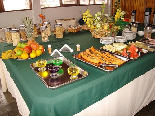 a table with a green table cloth with food and drinks at Del Rey Hotel in Barbacena