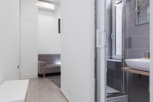 a bathroom with a gray chair and a sink at Core Apartments Zagreb in Zagreb