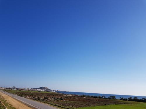 an empty road with the ocean in the background at Luxus Apartments in Kelibia