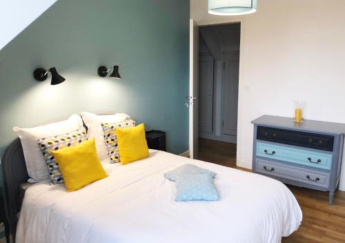 a bedroom with a white bed with yellow pillows at Il était une fois à l'Ouest "Lamballe-Armor" in Plestan