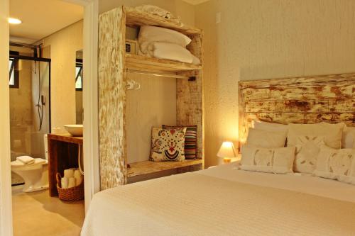 een slaapkamer met een bed en een badkamer bij Pousada Vivenda do Rosa in Praia do Rosa