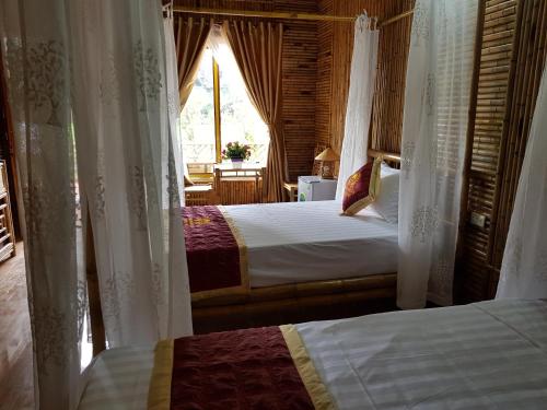 a bedroom with two beds with curtains and a window at Tam Coc Horizon Bungalow in Ninh Binh