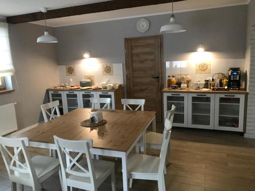 a kitchen with a wooden table and white chairs at Willa Malinka Wisła in Wisła